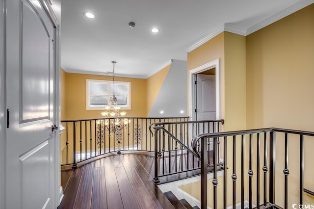 corridor with dark wood-type flooring, a notable chandelier, and crown molding