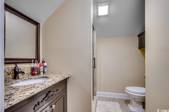 bathroom featuring lofted ceiling, tile flooring, toilet, and vanity