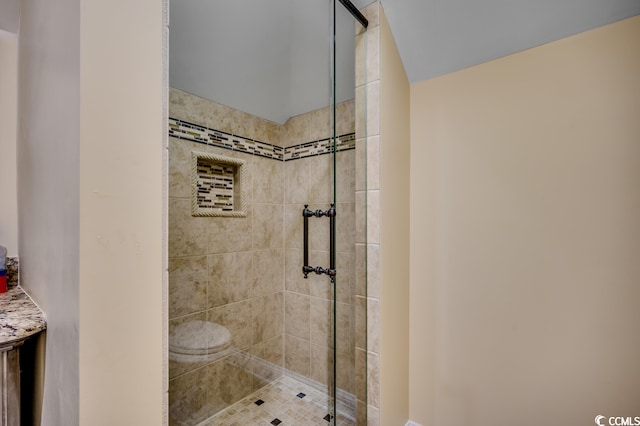 bathroom with tiled shower, toilet, and vanity