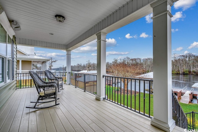 wooden deck with a water view and a lawn