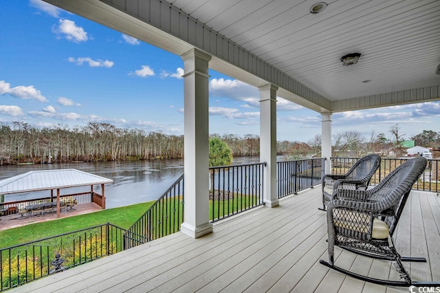 wooden terrace featuring a water view and a lawn