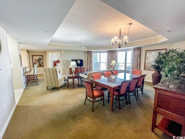 carpeted dining area featuring ceiling fan with notable chandelier, a raised ceiling, and a textured ceiling