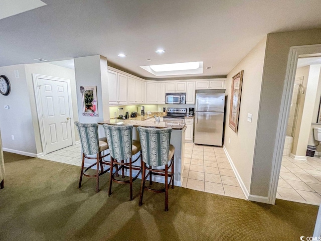 kitchen featuring appliances with stainless steel finishes, white cabinets, and light tile floors