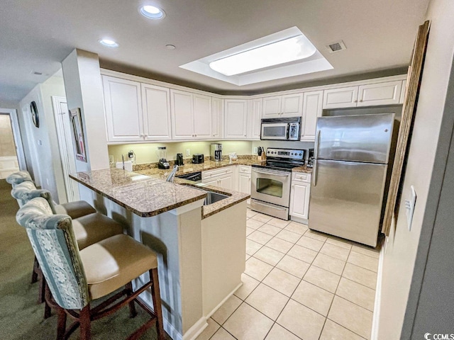 kitchen with white cabinets, sink, stainless steel appliances, and light stone countertops