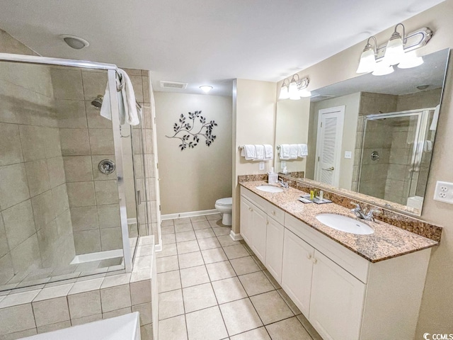 bathroom with tile flooring, vanity with extensive cabinet space, dual sinks, walk in shower, and toilet