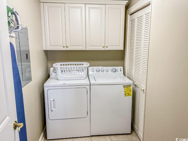 clothes washing area with washing machine and dryer, cabinets, and light tile floors