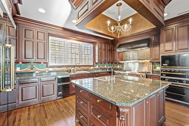 kitchen with decorative light fixtures, a kitchen island, sink, and extractor fan