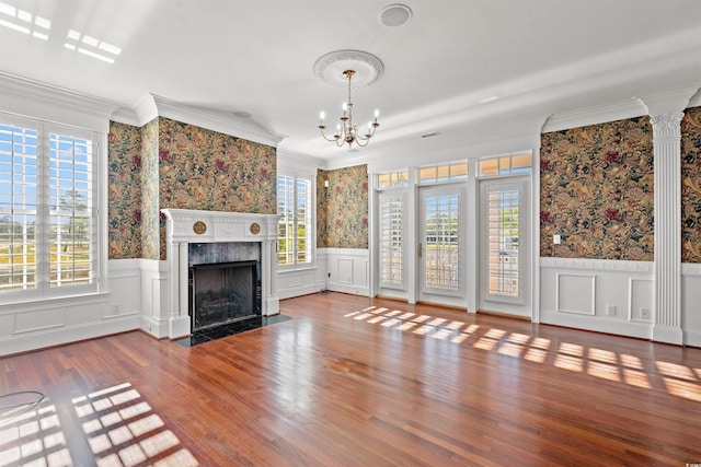 unfurnished living room with crown molding, a fireplace, a chandelier, and hardwood / wood-style flooring