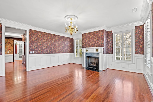 101 Greenwich Dr, Georgetown, SC 29440 - unfurnished living room featuring a chandelier, wallpapered walls, a premium fireplace, wood finished floors, and crown molding