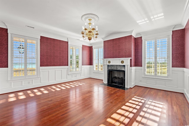 unfurnished living room with a premium fireplace, wood-type flooring, ornamental molding, and an inviting chandelier