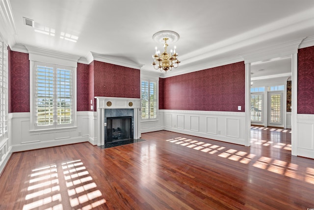 unfurnished living room with a fireplace, ornamental molding, hardwood / wood-style flooring, and a notable chandelier