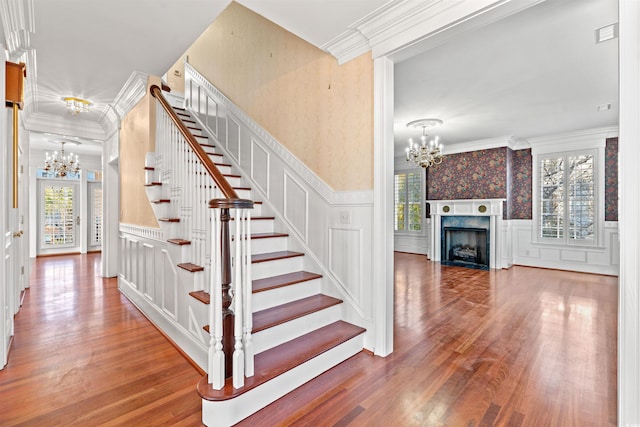 stairs with a wealth of natural light, a premium fireplace, crown molding, and wood-type flooring