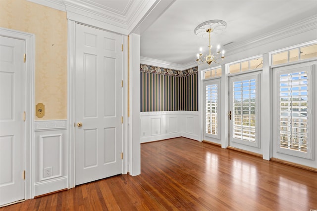 spare room with a chandelier, hardwood / wood-style flooring, and ornamental molding