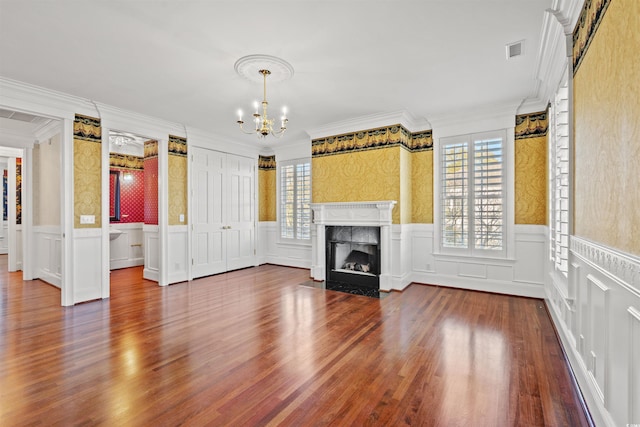 unfurnished living room featuring a high end fireplace, wood-type flooring, an inviting chandelier, and ornamental molding