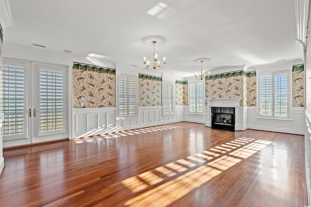 unfurnished living room with hardwood / wood-style floors, a notable chandelier, and crown molding