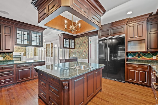 kitchen featuring a center island, sink, an inviting chandelier, light hardwood / wood-style flooring, and black refrigerator