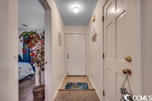 hall featuring a textured ceiling and light colored carpet