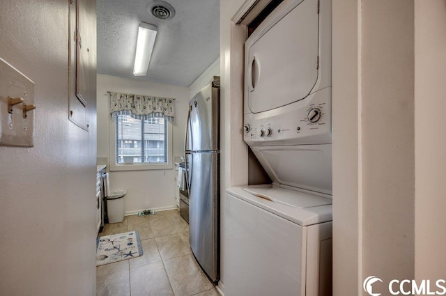 washroom featuring stacked washer / dryer and light tile floors