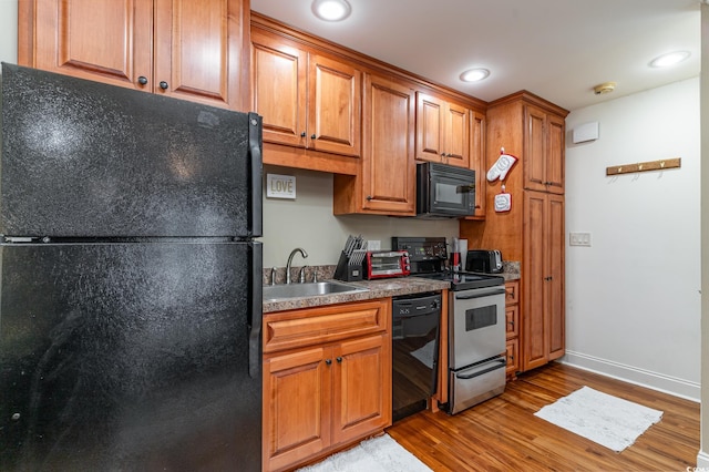 kitchen featuring black appliances, light hardwood / wood-style floors, and sink