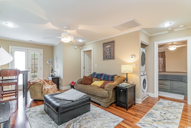 living room featuring stacked washer / drying machine, light wood-type flooring, and ornamental molding