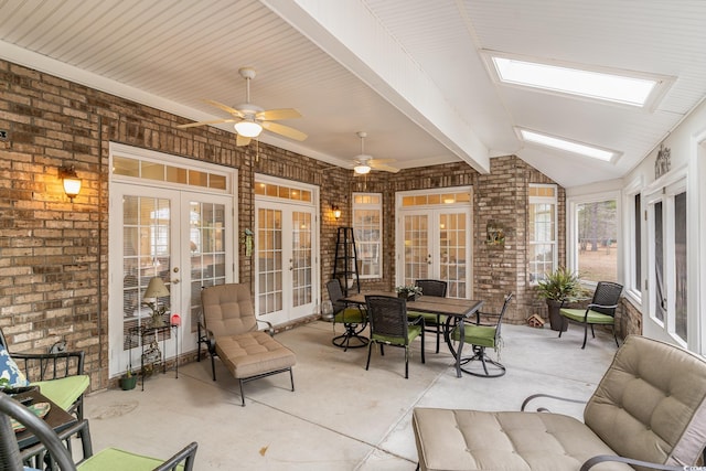 sunroom / solarium with vaulted ceiling with skylight, ceiling fan, and french doors