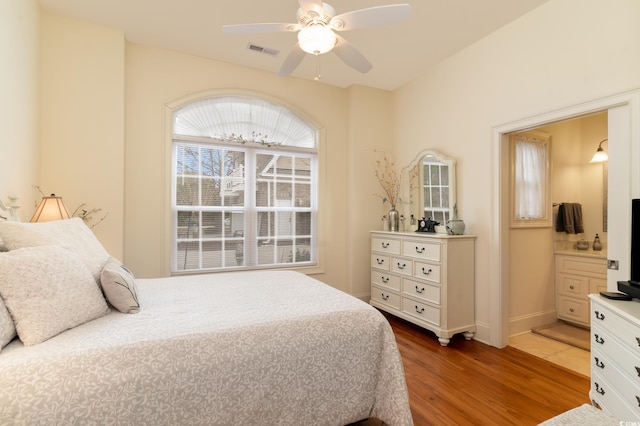 bedroom with hardwood / wood-style flooring, ensuite bath, and ceiling fan