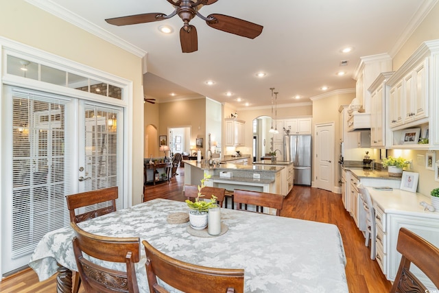 dining area with crown molding, dark hardwood / wood-style flooring, ceiling fan, and sink