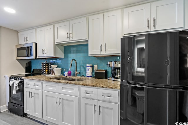 kitchen featuring light stone countertops, black appliances, white cabinetry, backsplash, and sink