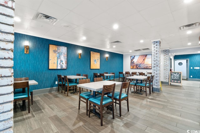 dining area featuring brick wall and light hardwood / wood-style flooring