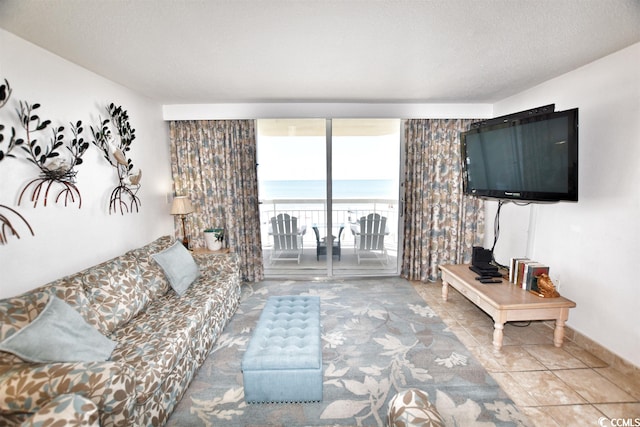 living room featuring a water view, light tile floors, and a textured ceiling