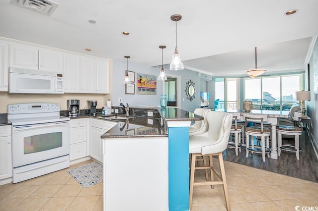 603 S Ocean Blvd Unit 1115, North Myrtle Beach, SC 29582 - kitchen featuring white appliances, a peninsula, a breakfast bar area, light tile patterned flooring, and white cabinetry