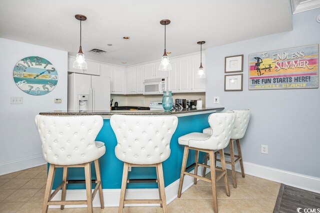 603 S Ocean Blvd Unit 1115, North Myrtle Beach, SC 29582 - kitchen with white appliances, white cabinetry, baseboards, a breakfast bar area, and dark countertops