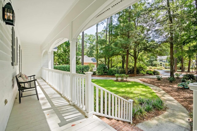 wooden terrace featuring a lawn and covered porch