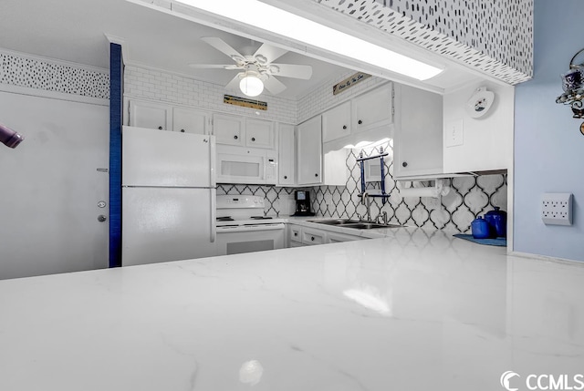 kitchen with white appliances, ceiling fan, sink, white cabinets, and backsplash