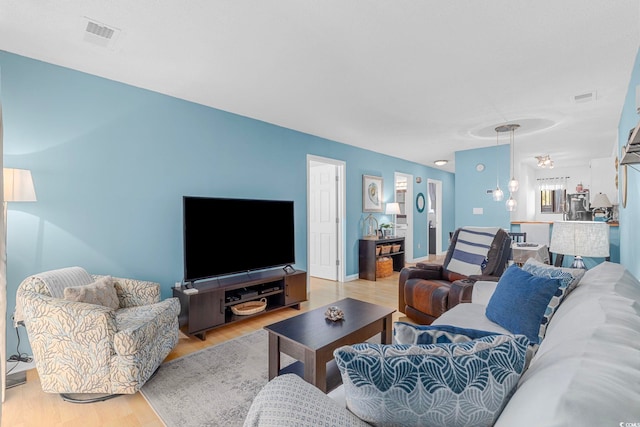 living room featuring a chandelier and light wood-type flooring