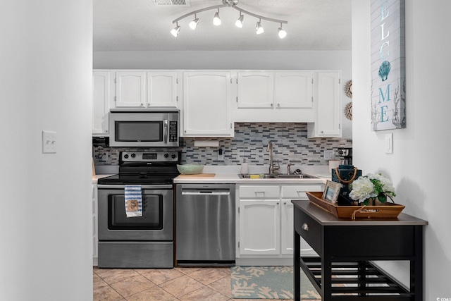 kitchen featuring stainless steel appliances, light tile flooring, a textured ceiling, white cabinets, and sink