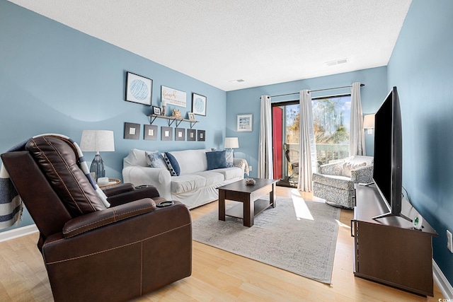 living room with a textured ceiling and light wood-type flooring