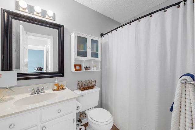 bathroom featuring toilet, large vanity, and a textured ceiling