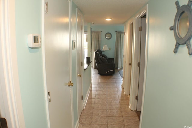 hallway with a textured ceiling and light tile flooring