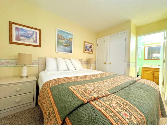 bedroom with connected bathroom, a textured ceiling, and carpet floors