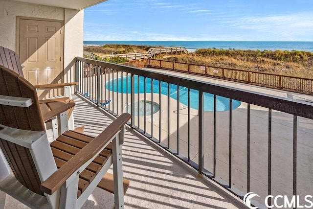 balcony with a water view and a fenced in pool