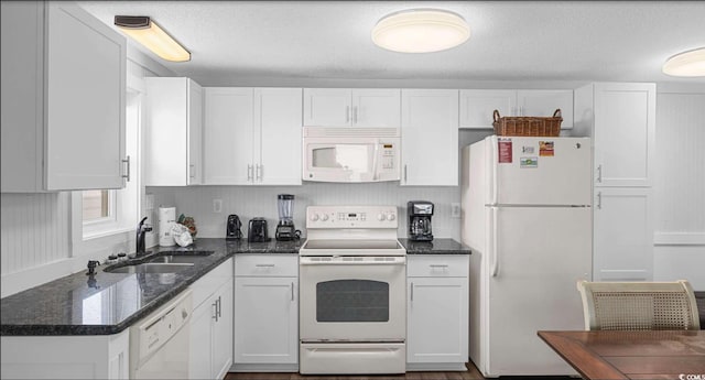 kitchen featuring sink, a textured ceiling, white appliances, dark stone counters, and white cabinets