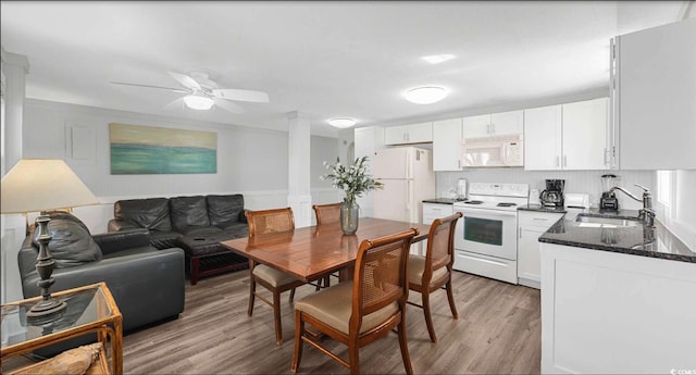 kitchen with white cabinetry, white appliances, light hardwood / wood-style floors, and sink