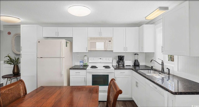 kitchen featuring dark stone countertops, sink, white appliances, and white cabinets