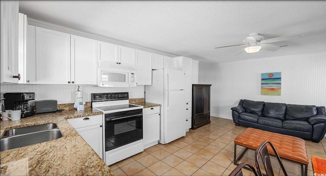 kitchen with sink, white appliances, light tile patterned floors, white cabinets, and stone countertops