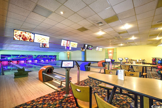 playroom featuring a bowling alley, a drop ceiling, and hardwood / wood-style flooring