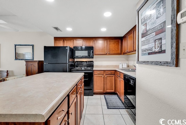 kitchen featuring a center island, light tile flooring, sink, and black appliances