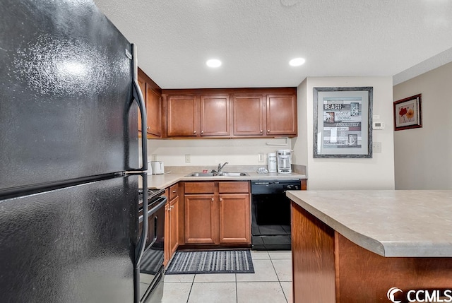 kitchen featuring light tile flooring, sink, black appliances, and a textured ceiling