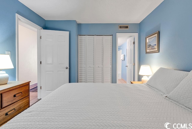 tiled bedroom with a textured ceiling and a closet