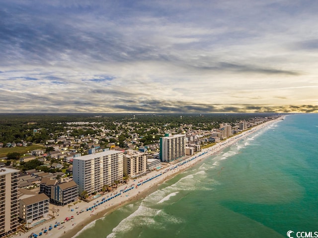 aerial view at dusk featuring a view of the beach and a water view